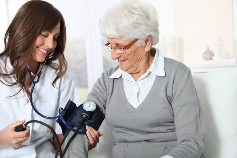 Closeup of nurse checking senior woman blood pressure